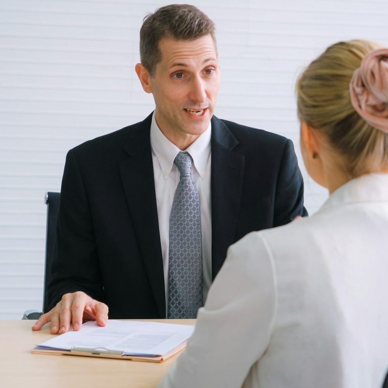 Ein Mann in Anzug führt ein Gespräch mit einer Frau im Büro.